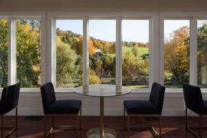 a room with a table and chairs in front of windows at Shelburne Springs Hotel in Shelburne Falls