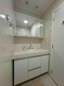 a white bathroom with a sink and white cabinets at Apartamento 01 quadra da praia - LUXO Praiamar Residence in Santos