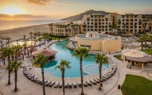 an aerial view of a resort with a pool and palm trees at Stunning 3BR Condo with Ocean Views, Golf Course & Resort Amenities in Cabo San Lucas
