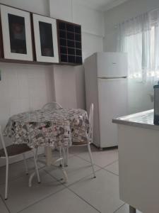 cocina con mesa, sillas y nevera en Apartment Vila Tupi, en Praia Grande