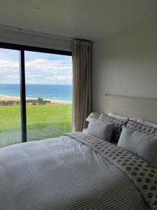 a bedroom with a bed and a large window at Ocean Beach in Tuki Tuki