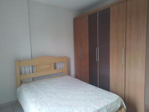 a bedroom with a bed and wooden cabinets at Apartment Vila Tupi in Praia Grande
