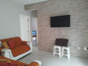 a living room with a couch and a tv on a brick wall at Apartment Vila Tupi in Praia Grande