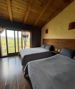 two beds in a room with a large window at Cabaña Bechamel, Tapalpa in Tapalpa