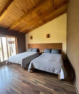 two beds in a large room with wooden floors at Cabaña Bechamel, Tapalpa in Tapalpa