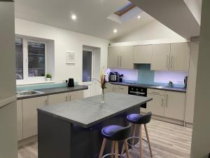 a kitchen with a large island with purple bar stools at Garden Close Suites in Ashford