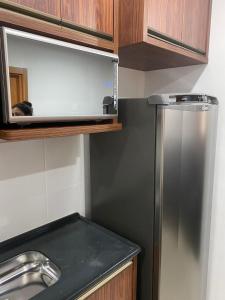 a kitchen with a stainless steel refrigerator and wooden cabinets at Apartamento Lindo e Aconchegante in São José