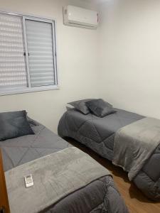 two beds in a room with a window at Apartamento Lindo e Aconchegante in São José
