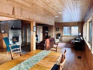een woonkamer met een houten tafel en een open haard bij Lazy Moose Lodge in Malone