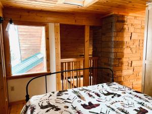 een slaapkamer met een bed in een blokhut bij Lazy Moose Lodge in Malone
