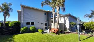 a house with palm trees and a bench in the yard at Aquila Haven in Whitianga