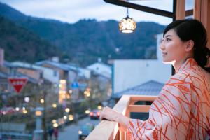 Una donna in piedi su un balcone che guarda una città di Sumihei Bettei Toki Toki a Kinosaki