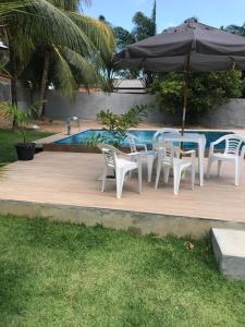 uma mesa e cadeiras com um guarda-sol ao lado de uma piscina em Casa Marudá em Marapanim