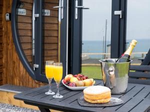 a table with two glasses of orange juice and a plate of fruit at Traeth Pod - Uk46077 in Towyn