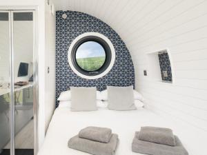 a bedroom with a bed with a round window at Traeth Pod - Uk46077 in Towyn