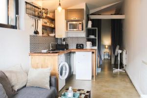 a living room with a couch and a kitchen at Practical and charming love cocoon with garden in Pierrefitte-sur-Seine