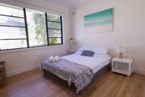 a bedroom with a bed and two windows at Coastal 3 bedroom house with private oasis. in Mona Vale