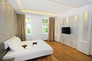 a bedroom with a white bed and a flat screen tv at Aurellia Deluxe Apartments in Vienna