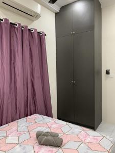 Rosevilla Homestay - 3R2B Fully Aircond WiFi في Bandar Puncak Alam: غرفة نوم مع سرير وخزانة أرجوانية