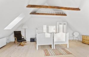 een zolderkamer met witte meubels en een stoel bij 2 Bedroom Beautiful Home In Rudkbing in Rudkøbing