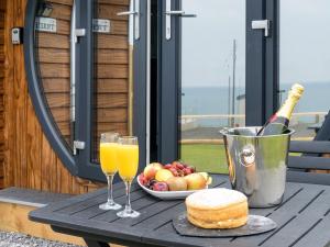 a table with two glasses of orange juice and a plate of fruit at Ynys Pod - Uk46078 in Gwbert