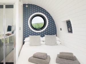 a bedroom with a white bed with a round mirror at Ynys Pod - Uk46078 in Gwbert