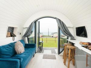 a living room with a blue couch in a tiny house at Ynys Pod - Uk46078 in Gwbert