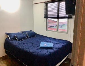 una camera da letto con un letto con cuscini blu e una finestra di Apartamento zona central - paloquemao a Bogotá