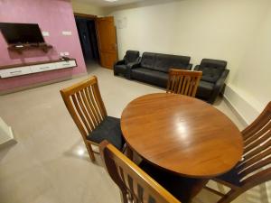 Hotel Sree Gokulam Apartments في غوروفايور: غرفة طعام مع طاولة وكراسي وأريكة