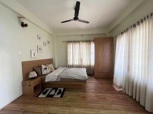 a bedroom with a bed and a ceiling fan at Zion Apartments, Pokhara in Pokhara