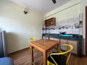 a kitchen with a wooden table and yellow chairs at Zion Apartments, Pokhara in Pokhara