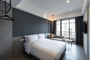 ein Schlafzimmer mit einem großen weißen Bett und einer Couch in der Unterkunft Hotel Euphemia in Taichung