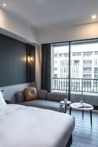 pokój hotelowy z łóżkiem, kanapą i oknem w obiekcie Hotel Euphemia w mieście Taizhong