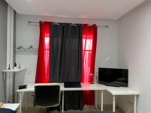 uma secretária com um computador e cortinas vermelhas em Cozy & Confort au cœur de Kenitra em Kenitra