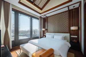 - une chambre avec un lit blanc et une grande fenêtre dans l'établissement Yangzhou Mangdao Garden Resort, à Yangzhou