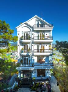 a tall white building with balconies and trees at The Grandview Villa Dalat in Da Lat