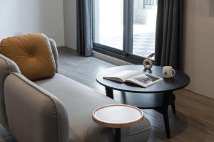 a living room with a chair and a table with a book at Hotel Euphemia in Taichung