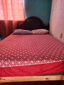 a bed with a red and white comforter on it at Hostal Bravo Vallarta in Puerto Vallarta