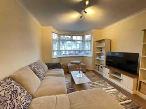 a living room with a couch and a flat screen tv at Cosy House near Harry Potter Studios in Leavesden Green