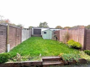 a backyard with a fence and a green yard at Cosy House near Harry Potter Studios in Leavesden Green