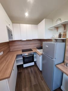 a small kitchen with white cabinets and a refrigerator at Charmant 3 pièces in Choisy-le-Roi