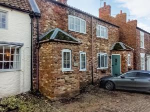 an old brick house with a car parked outside at Half Moon Cottage in Brafferton