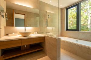 a bathroom with a sink and a tub and a mirror at Yuzen in Kutchan