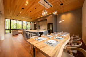 a dining room with a long table and a kitchen at Yuzen in Kutchan