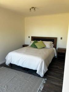 een slaapkamer met een wit bed met groene kussens bij Cabaña en Puerto Varas, Chile. in Puerto Varas
