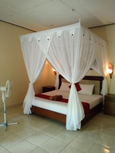 a bedroom with two beds with white drapes at Pondok Aldi in Amed