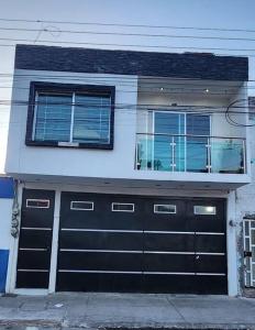 une maison avec deux portes de garage et deux fenêtres dans l'établissement departamento Saturno, à Guadalajara