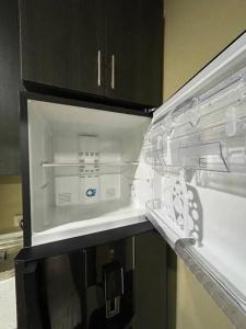 um frigorífico vazio com a porta aberta numa cozinha em Lomeli’s Home, 5 minutos del Tunco em La Libertad