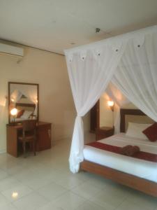una camera con letto, scrivania e specchio di Pondok Aldi ad Amed