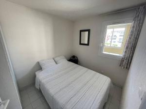 ein kleines Schlafzimmer mit einem weißen Bett und einem Fenster in der Unterkunft Appartement Cap d'Agde, 3 pièces, 6 personnes - FR-1-723-54 in Cap d'Agde